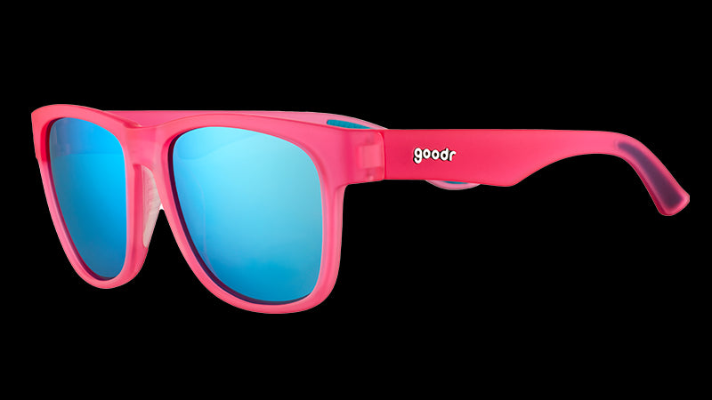 Vue de trois quarts d'angle de lunettes de soleil roses de forme carrée et à large monture, avec des verres réfléchissants bleus.
