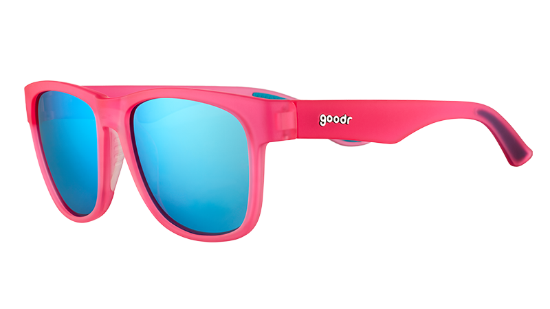 Vue de trois quarts d'angle de lunettes de soleil roses de forme carrée et à large monture, avec des verres réfléchissants bleus.