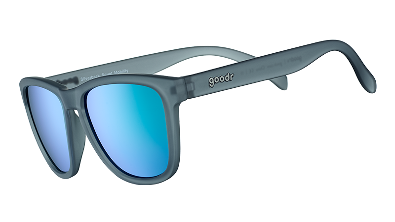 Vue de trois quarts d'angle de verres solaires de forme carrée avec une monture translucide grise et des lentilles réfléchissantes vertes.