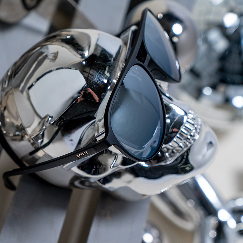 Vue latérale de lunettes de soleil d'aviateur noires et chromées présentées sur un crâne chromé.